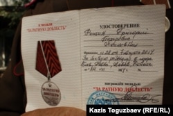 Григорий Рощин медаль ғана емес, оған қосымша берілетін әлдебір куәлікті де көрсетті. Алматы, 17 қыркүйек 2014 жыл.