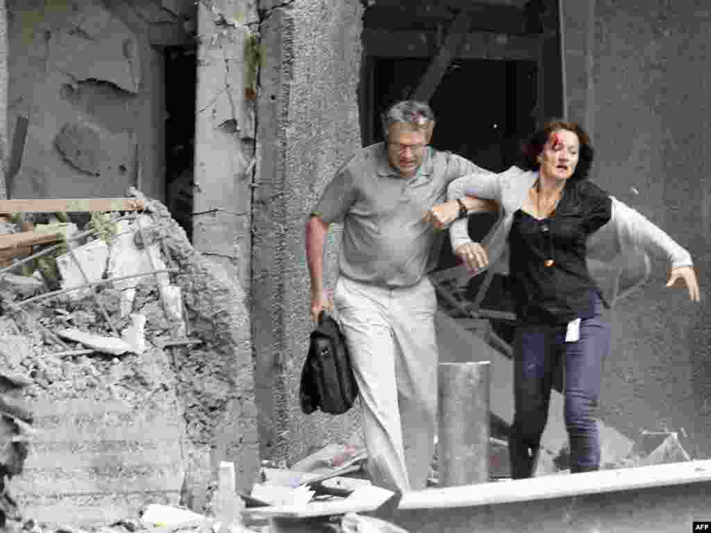 A man helps a wounded woman evacuating a building after a bomb attack near government offices in Norway's capital, Oslo, on July 22. Seven people died in the explosion and scores more were killed in a related shooting incident on the island of Otueya.Photo by Morten Holm for AFP