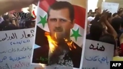 Участники антиправительственных акций жгут портрет сирийского президента Башара Асада 