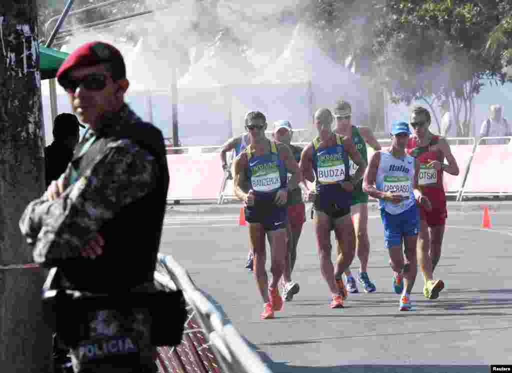 Competitors get some welcome relief from the searing heat while passing through a mist station in the men's 50-kilometer walk.