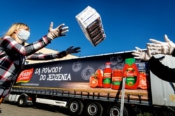 Рабочие загружают продукты в грузовик в Польше. Две польские компании, Polski Cukier и Polskie Przetwory, пожертвовали продукты питания нуждающимся.