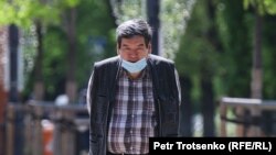 Мужчина в защитной маске идет по улице. Алматы, 1 мая 2020 года.