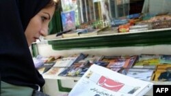 An Iranian woman reads the front page of "Sharq" in Tehran.