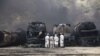 Men stand near NATO supply tankers destroyed by fire near the town of Hub.