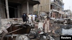 Residents inspect the site of a bomb attack that in Basra on May 10, one of a series of deadly attacks.