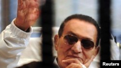 Egypt -- Former President Hosni Mubarak waves to his supporters inside a cage in a courtroom at the police academy in Cairo, April 13, 2013