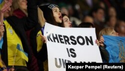 Вболівальниця з плакатом англійською мовою «Херсон – це Україна» під час футбольного матчу «Динамо»
