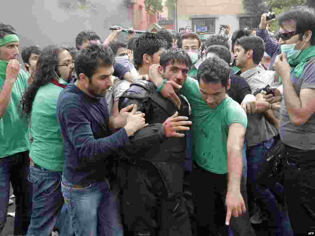 Protesters try to help a riot policeman who was beaten during the street clashes.