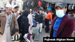 A youth wearing a mask walks in crowded downtown Kabul.