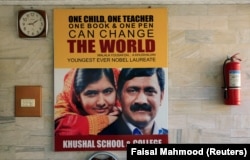 A poster with the pictures of Nobel Peace Prize winner Malala Yousafzai and her father Ziauddin Yousufzai hangs at the wall of Khushal School, in her home district in Swat Valley