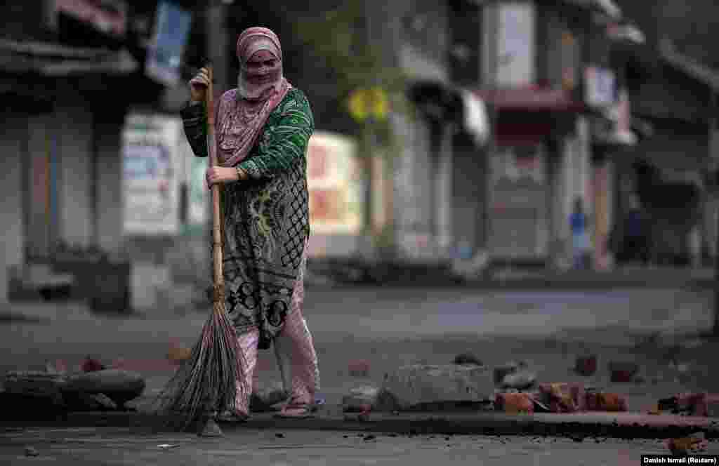 A woman removes rubble from a road on the Indian side of the restive Kashmir region. (Reuters/Danish Ismail)