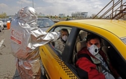 Працівники іранського Червоного Півмісяця перевіряють температуру подорожніх на шосе біля Тегерану, 26 березня 2020 року