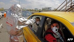 Members of Iranian Red Crescent test people with possible coronavirus Covid-19 symptoms, as police blocked Tehran to Alborz highway to check every car following ordered by the Iranian government, outside Tehran, March 26, 2020