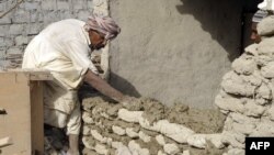 A quake survivor rebuilds a wall of his damaged mud-brick house in Awaran district. Many such houses are reported to be uninhabitable, if they didn't already collapse.