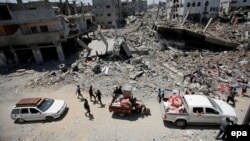 Palestinians carry their belongings next to the rubble of destroyed houses in Gaza City on August 1.