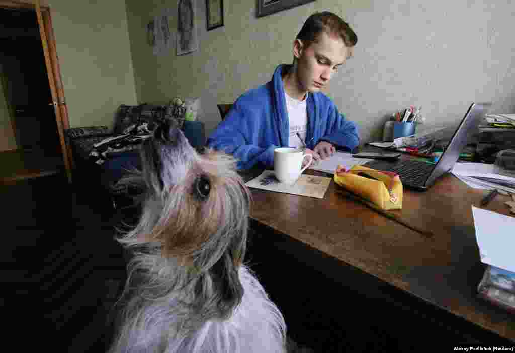 Yegor Pavlishak studies in his bathrobe alongside his dog, Pinky, in Yevpatoriya, Ukraine.&nbsp; 