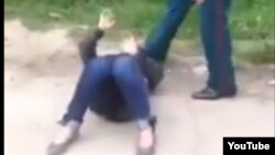 Скриншот видеозаписи, на которой инспектор Иззатилла Хашимов пинает лежащую на земле больную женщину. 