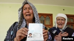 Беженка-узбечка (слева) держит в руках паспорт ее сына, убитого в межэтнических стычках. Джалалабад, Кыргызстан, 21 июня 2010 года.