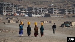Kuchi women carry water on their heads on the outskirts of Kabul in late November.