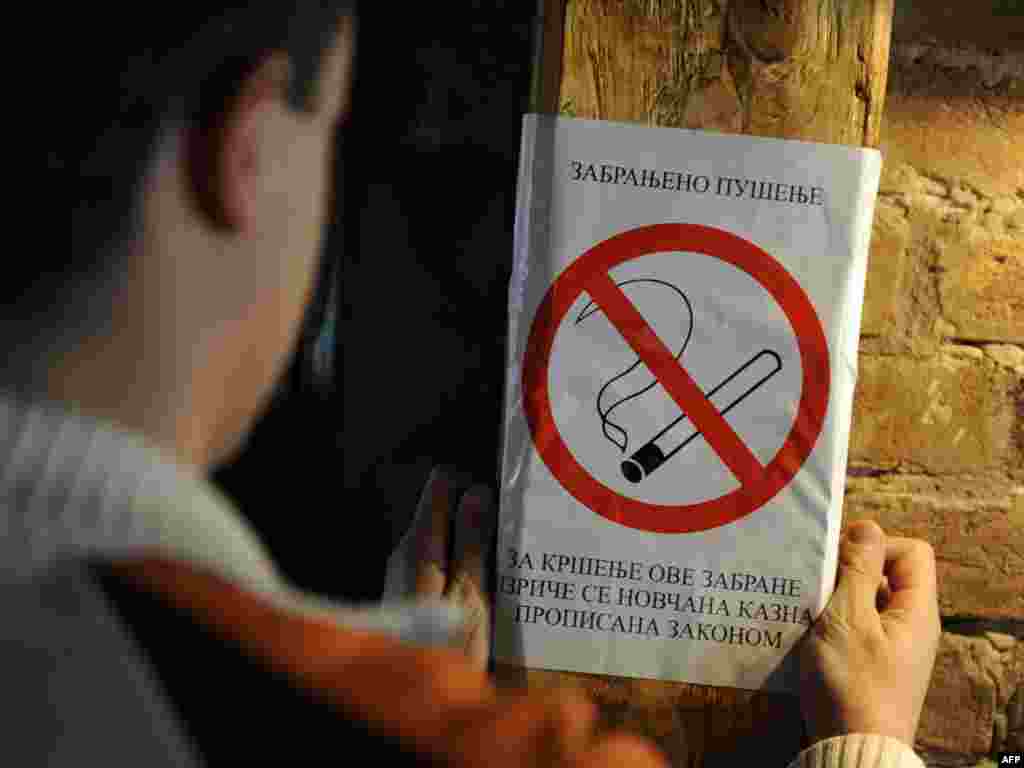 A barkeeper places an nonsmoking poster inside a Belgrade cafe on November 11. Serbia introduced on tough antitobacco measures, the strictest ever in the Balkans country, where some 33.6 percent of adults smoke. Photo by Andrej Isakovic for AFP