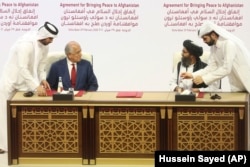 U.S. peace envoy Zalmay Khalilzad (left) and Mullah Abdul Ghani Baradar, the Taliban group's top political leade, sign a peace agreement between Taliban and U.S. officials in Doha on February 29, 2020.