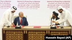 U.S. peace envoy Zalmay Khalilzad (left) and Mullah Abdul Ghani Baradar, the Taliban's top political leader, sign the peace agreement between Taliban and U.S. officials in Doha on February 29, 2020.