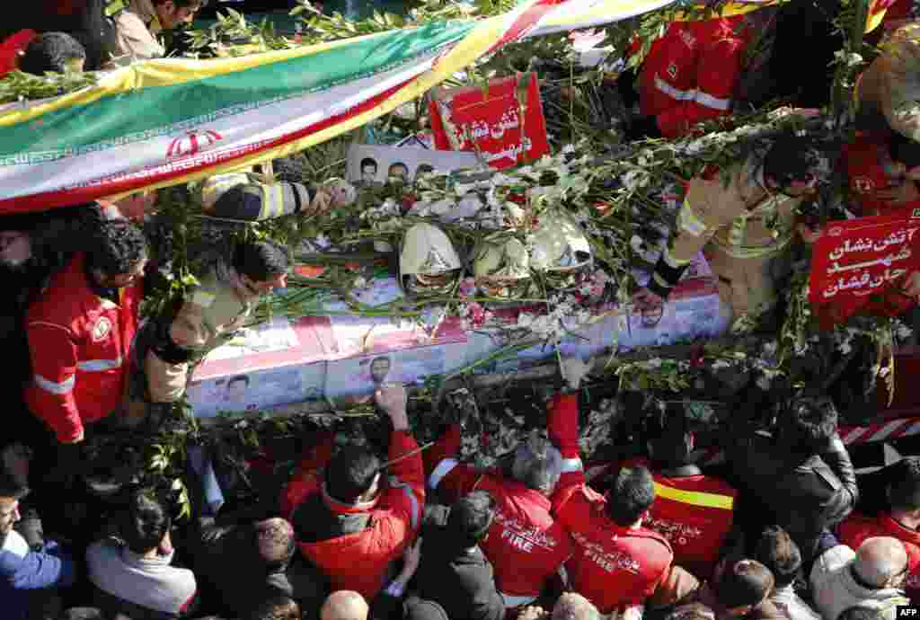 Iranian firefighters and mourners gather around a truck carrying the coffins of firemen killed when Tehran&#39;s oldest high-rise collapsed after a fire. At least 11 firefighters were killed, along with four civilians, in the January 19 disaster. (AFP/Atta Kenare)