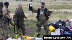 S-au împlinit ieri opt ani de la doborârea, de către separatiștii pro-ruși din Donbas, a avionului de pasageri Malaysia Airlines  (MH17) deasupra satului Hrabove, în Donețk, pe 17 iulie, 2014. Aici - luptător separatist arătând o jucărie găsită în resturile epavei avionului. 