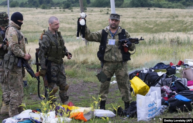 Бойовик російських гібридних сил тримає іграшку, виявлену на місці падіння уламків «Боїнга», збитого російською установкою «Бук», в результаті чого загинуло 298 людей, в тому числі 80 дітей. Донеччина, неподалік села Грабове, 19 липня 2014 року