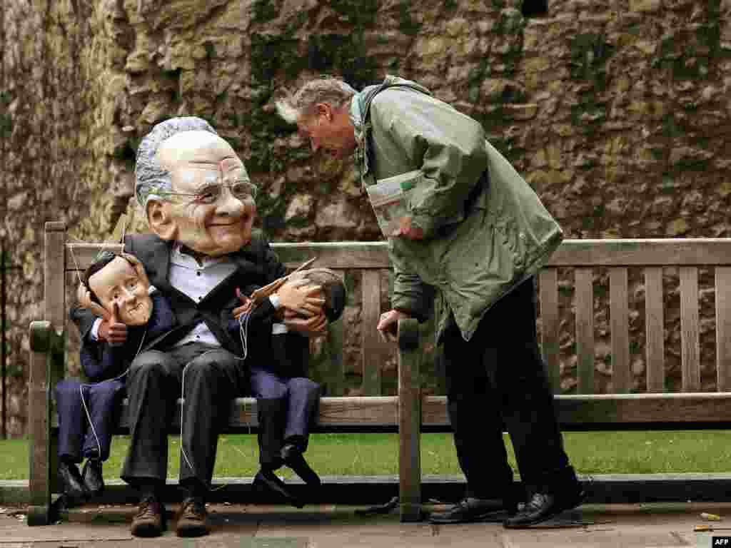 The Reverend David James (right) speaks with a demonstrator dressed in a Rupert Murdoch mask while holding puppets of British Prime Minister David Cameron and British Minister for Culture, Media and Sport Jeremy Hunt, during a protest against Murdoch's proposed takeover of BSkyB, in London.Photo by Adrian Dennis for AFP