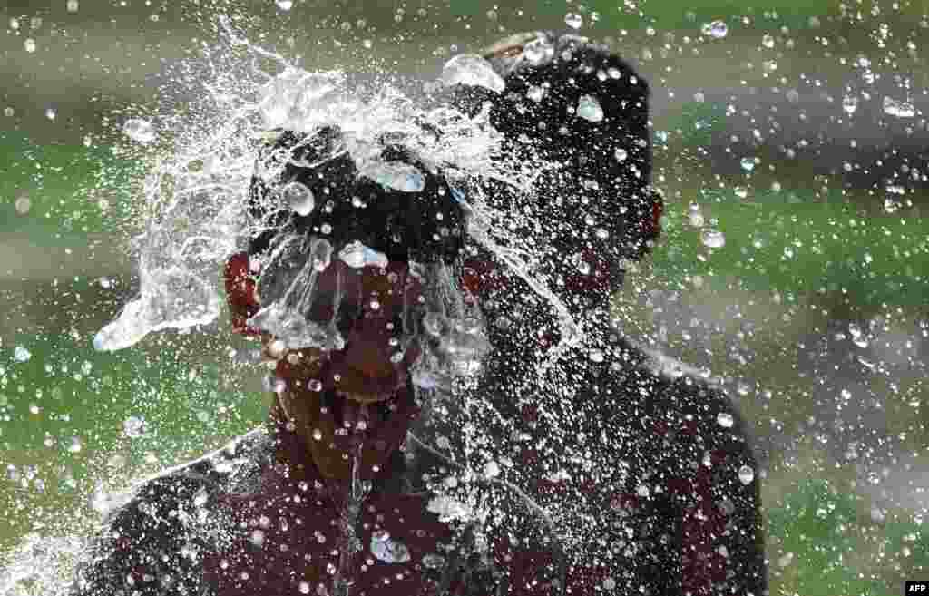 Indian children use a roadside tap to cool off amid rising temperatures in Allahabad on May 17 (AFP/Sanjay Kanojia)