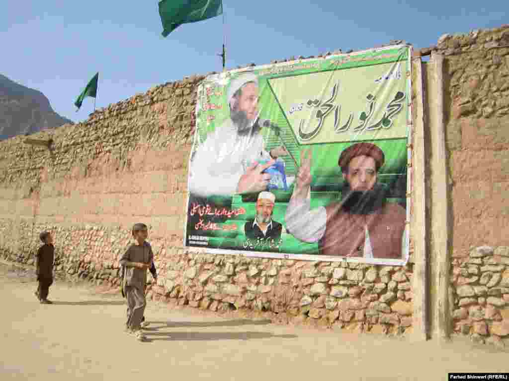 Pakistani boys walk past an election campaign poster in the country&#39;s tribal region. (Farhad Shinwari/RFE/RL)