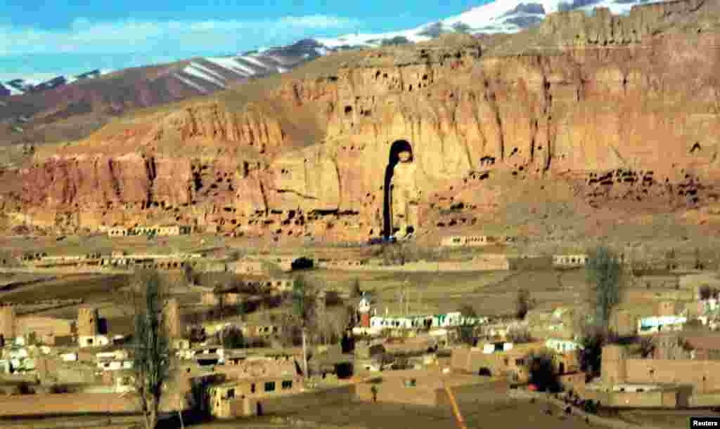 Afghanistan -- A scene of the large Buddah that soars 53 metres (174 feet) and a small town lying at the very heart of the Hindu Kush mountains in a beautiful valley containing one of most remarkable achievemnts - the Colossal Buddhas of Bamiyan in the ca