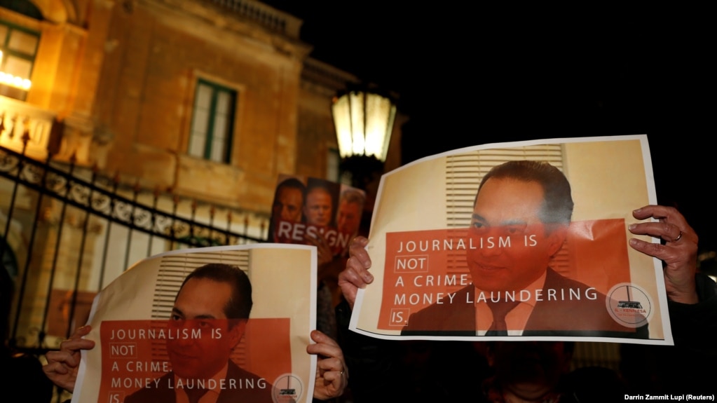 Protestors hold up posters showing Pilatus Bank chairman Ali Sadr Hashemi Nejad while calling for the resignation of Malta's police commissioner, outside police headquarters in Floriana, March 21, 2018