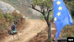 Албанија- човек на магаре поминува покрај знамето на ЕУ во близина на Тирана 