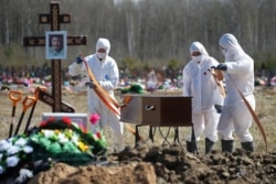 Gravediggers wearing personal protective equipment carry a coffin while burying a COVID-19 victim near St. Petersburg on May 6.