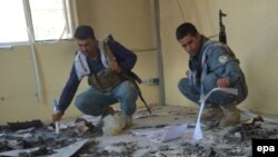 Afghan police check a damaged building after they took over control of the Char Darra district of Kunduz Province on July 1.