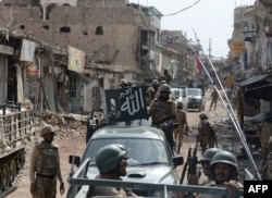 FILE: Pakistani soldiers patrol through a destroyed bazaar in Miran Shah in July 2014.
