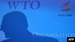 Силуэт человека на баннере с официальным логотипом ВТО. Иллюстративное фото.