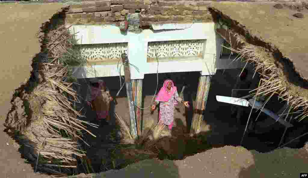 ک زن پاکستانی از میان خرابی حاصل از شلیک در سقف خانه&zwnj;اش دیده می&zwnj;شود. این حمله در روستای &laquo;دامالا حکیم&zwnj;والا&raquo; در استان پنجاب انجام شده است 