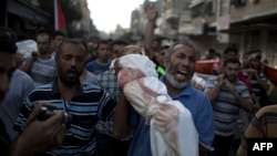A Palestinian man cries as he carries the body of 1-year-old Noha Mesleh, who died of wounds sustained after a UN school in Beit Hanun was hit by an Israeli tank shell, during her funeral in Beit Lahia, northern Gaza Strip, on July 25.