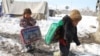 Displaced children carry winter supplies distributed by aid workers on the outskirts of Kabul on January 1. 