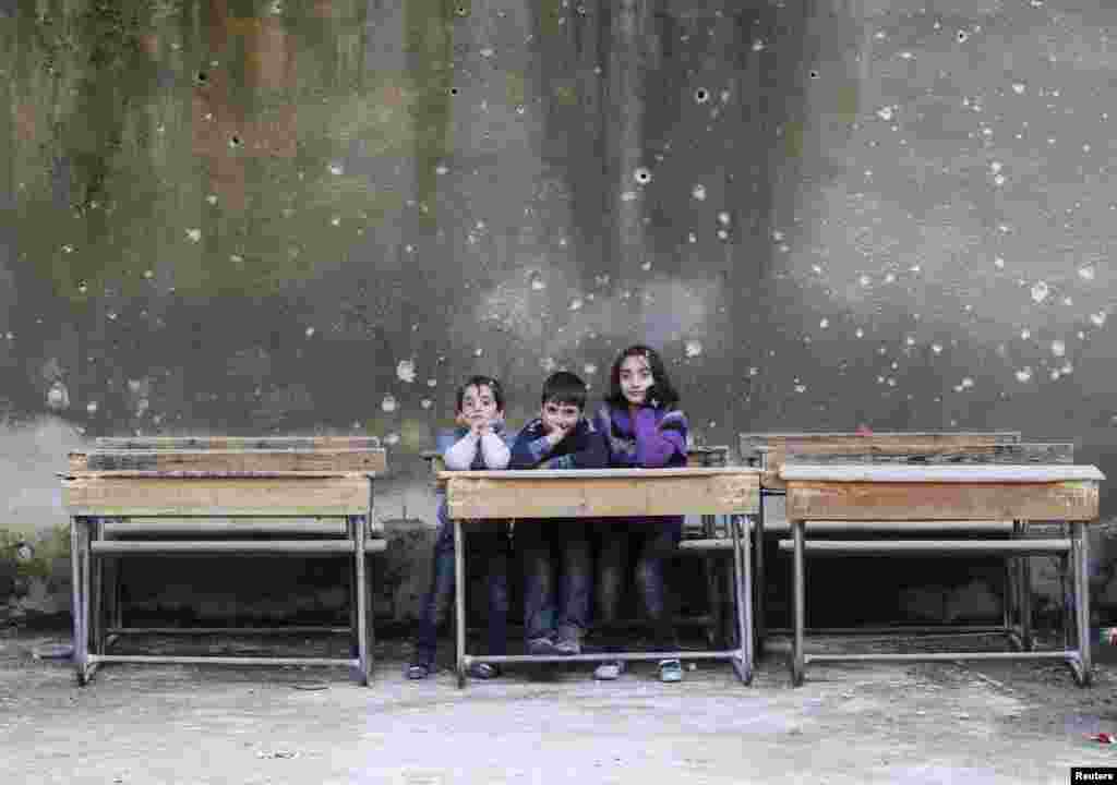 Children sit on school benches at the Al-Tawheed school in the besieged Syrian city of Aleppo. (Reuters/Muzaffar Salman)