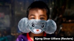 Панджі, 8 років, він носить маску у вигляді звірятка, щоб допомогти запобігти поширенню коронавірусу в Джакарті, Індонезія. 2 квітня 2020 року