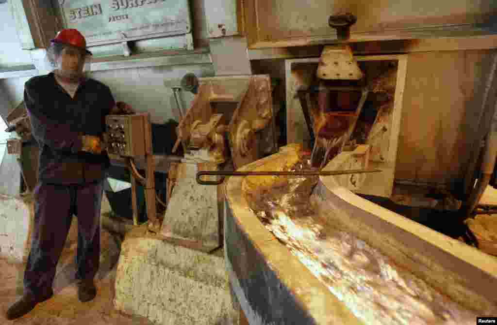 An employee supervises the flow of melted aluminum at the foundry.