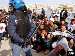 Итальянский полицейский и беженцы из Северной Африки. Остров Лампедуза, юг Италии