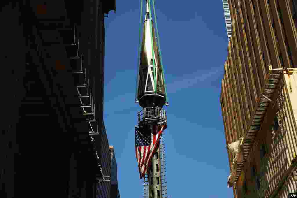 The 408-foot spire is hoisted onto a temporary platform on the top of One World Trade Center in New York. The piece will be attached at a later date.