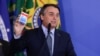  Jair Bolsonaro, vorbind la înscăunarea în funcție a Eduardo Pazuello ca ministru al sănătății. Ține în mână o cutie de hydroxychloroquine. Septembrie 2020.