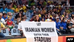 A woman holds a banner reading "Let Iranian women enter their stadiums" during the men's qualifying volleyball match between Russia and Iran at the Rio 2016 Olympic Games in Brazil.