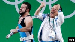 Nijat Rahimov, left, of Kazakhstan is celebrated by a member of the coaching staff after a world record attempt in Clean & Jerk in the men's 77kg category final of the Rio 2016 Olympic Games Weightlifting events on August 10.